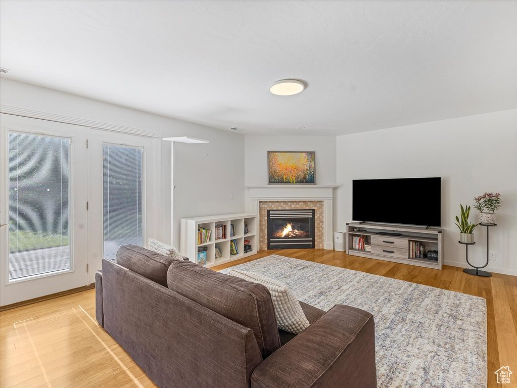 Living room with a tile fireplace, light wood-type flooring, and baseboards