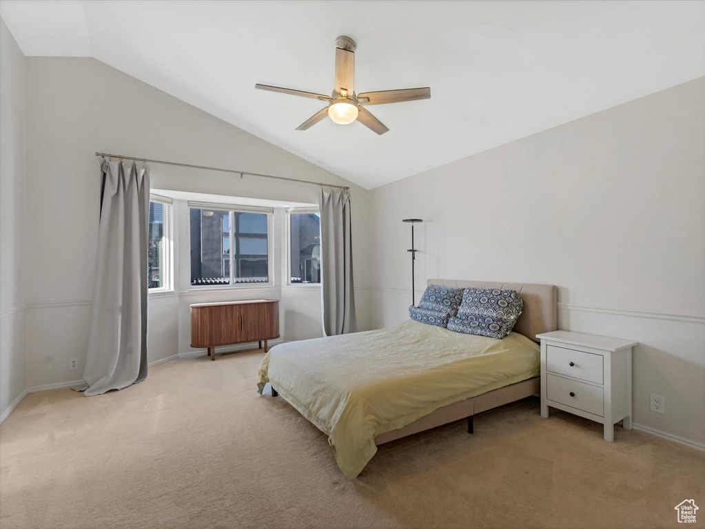 Bedroom with lofted ceiling, light colored carpet, radiator, baseboards, and ceiling fan