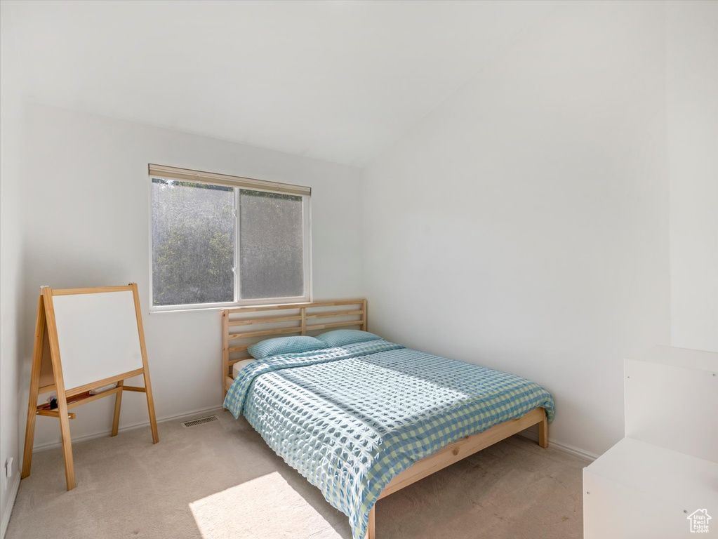 Carpeted bedroom with baseboards and vaulted ceiling