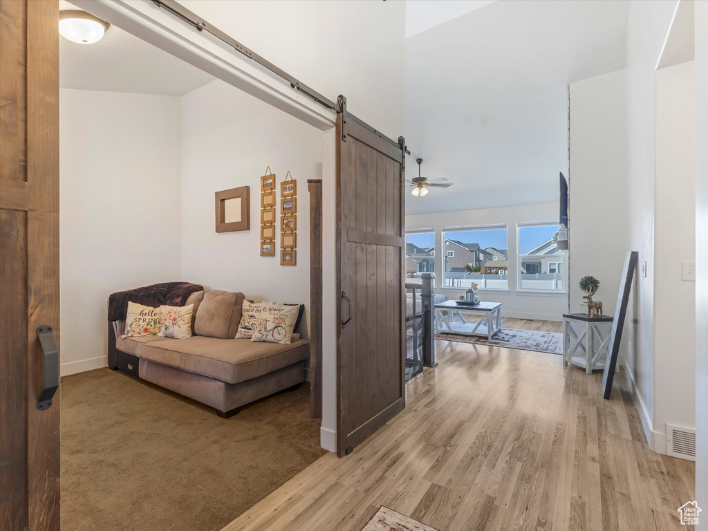 Hall featuring a barn door, light wood-type flooring, and baseboards