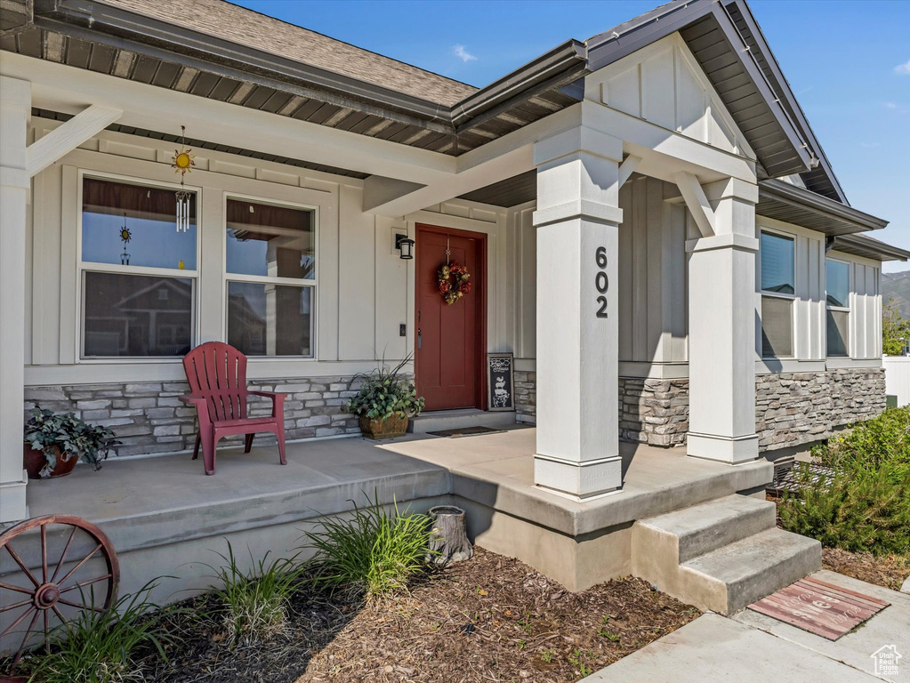 Entrance to property with a porch, stone siding, and board and batten siding