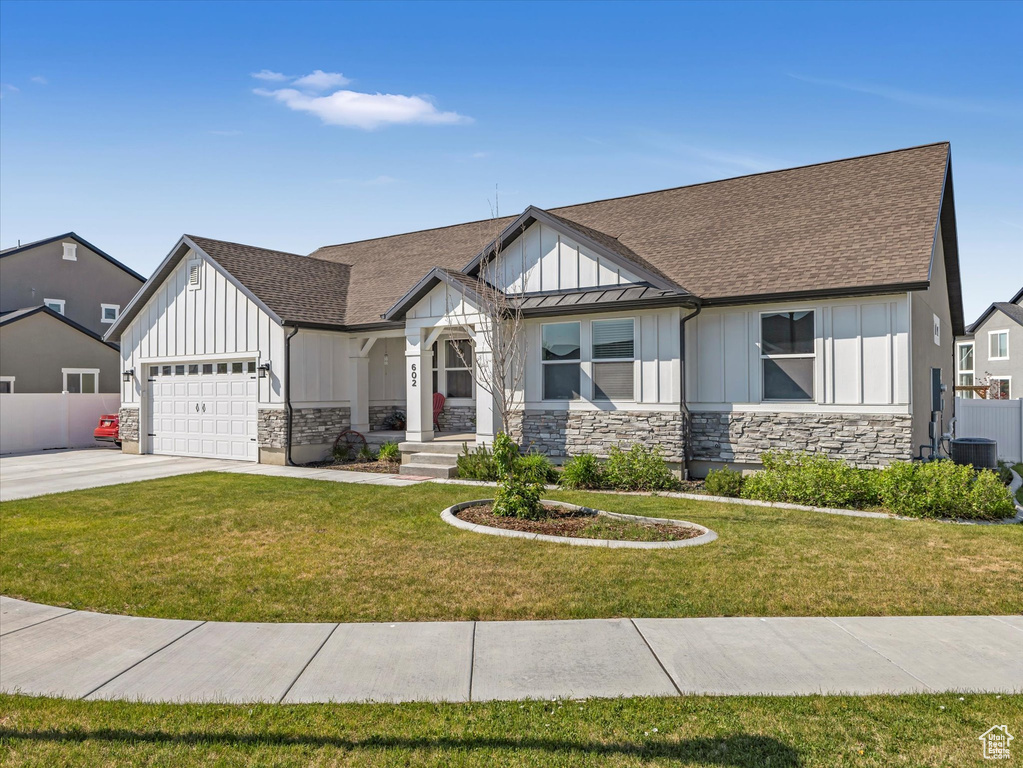 View of front of home with board and batten siding, stone siding, an attached garage, driveway, and a shingled roof