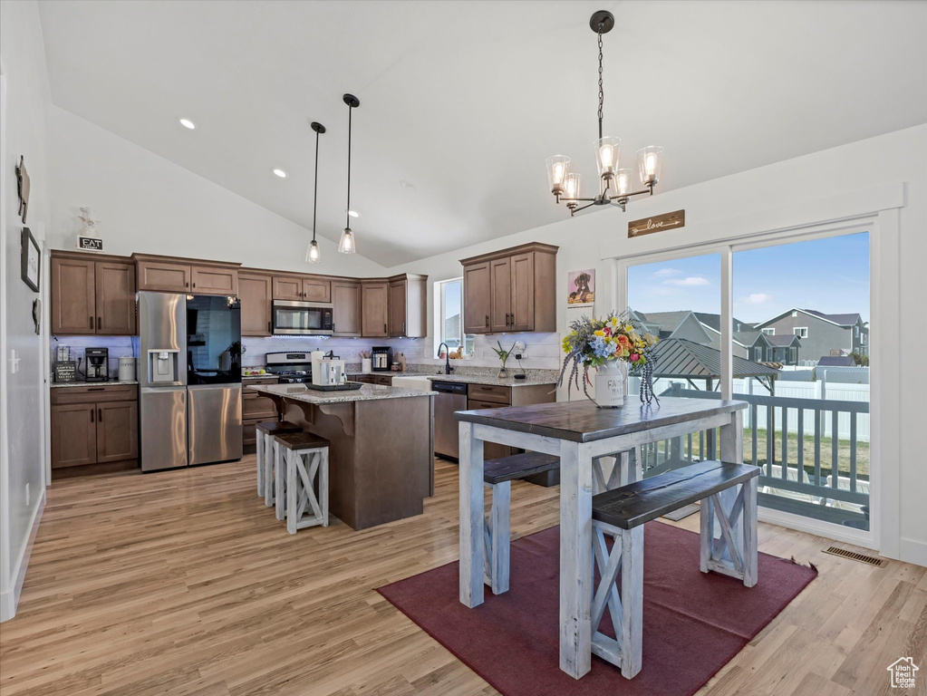 Dining room with a chandelier, light wood-style flooring, high vaulted ceiling, and recessed lighting