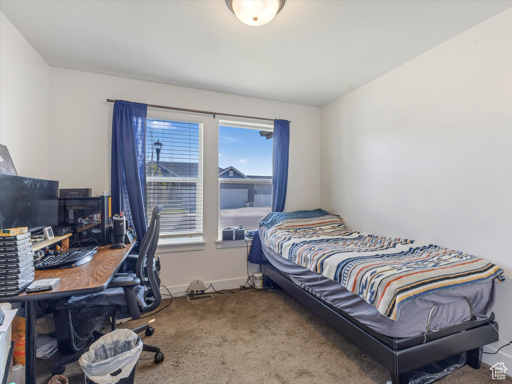 Carpeted bedroom featuring an office area and baseboards