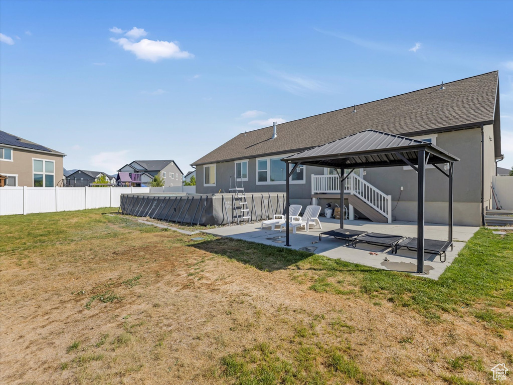 Back of property featuring a gazebo, a patio, roof with shingles, and a residential view