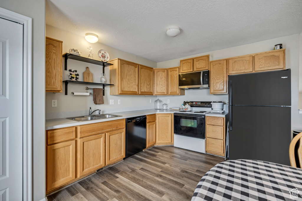 Kitchen featuring black appliances, a sink, light countertops, dark wood finished floors, and open shelves