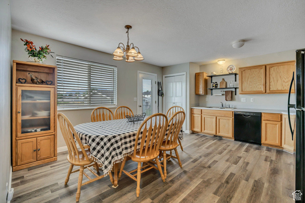 Dining room with light wood-style flooring, a chandelier, a textured ceiling, and baseboards