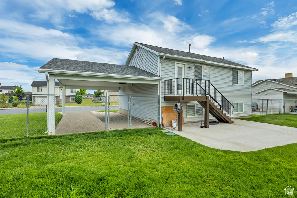Back of property with a gate, a carport, a patio, and a shingled roof