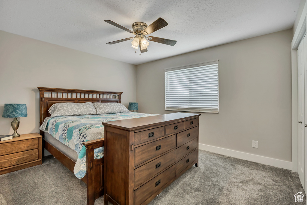 Bedroom featuring light colored carpet, baseboards, and a ceiling fan