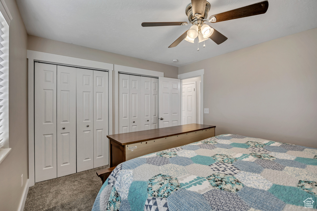 Bedroom featuring carpet, multiple closets, and a ceiling fan
