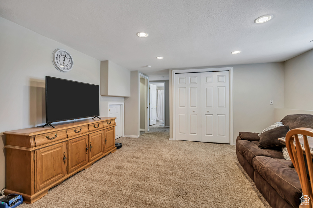 Living area with recessed lighting, light carpet, and baseboards