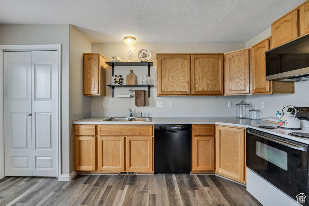 Kitchen with black dishwasher, electric range, a sink, dark wood-type flooring, and light countertops