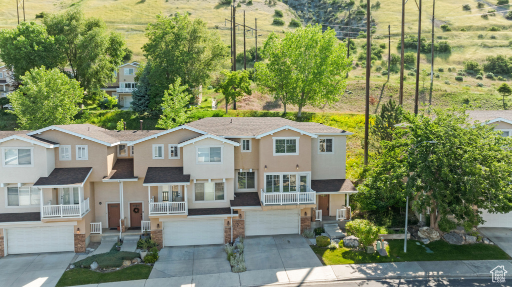View of front of house featuring a garage, driveway, stucco siding, and roof with shingles