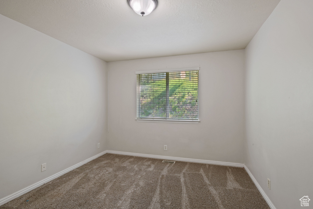 Empty room featuring carpet and baseboards