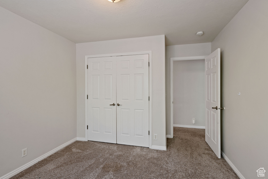 Unfurnished bedroom with carpet, a closet, and baseboards