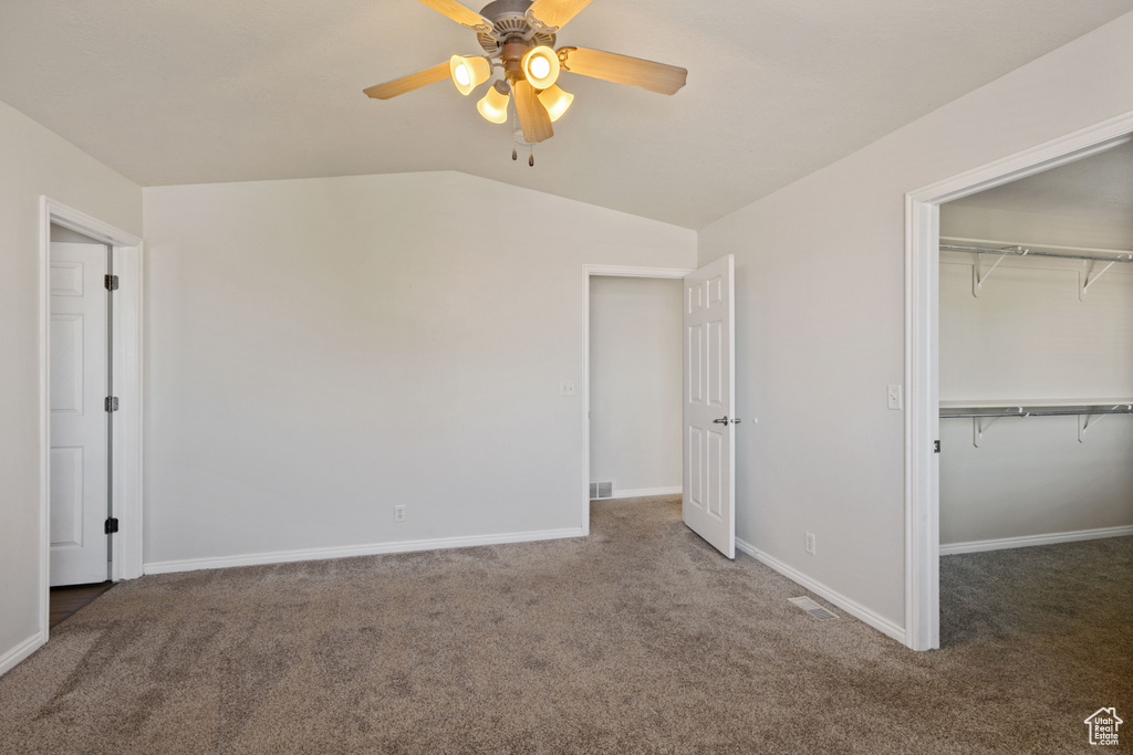 Unfurnished bedroom with carpet, vaulted ceiling, a closet, baseboards, and ceiling fan