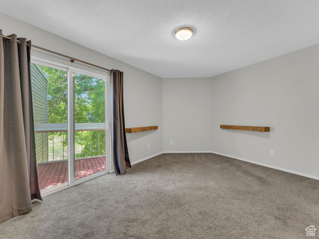 Carpeted spare room featuring baseboards and a textured ceiling