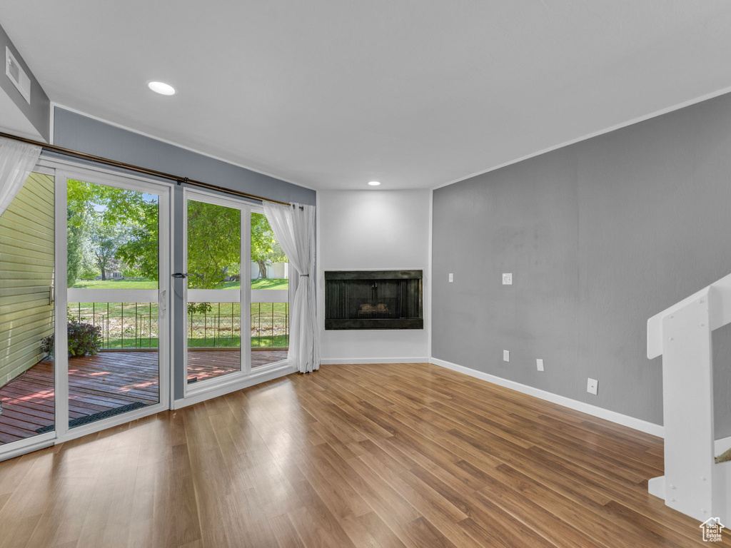 Unfurnished living room with baseboards, wood finished floors, a multi sided fireplace, and recessed lighting
