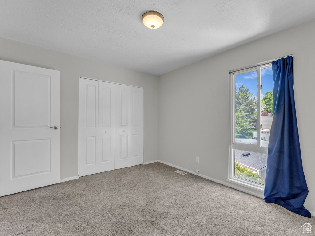 Unfurnished bedroom with carpet floors, a closet, and baseboards