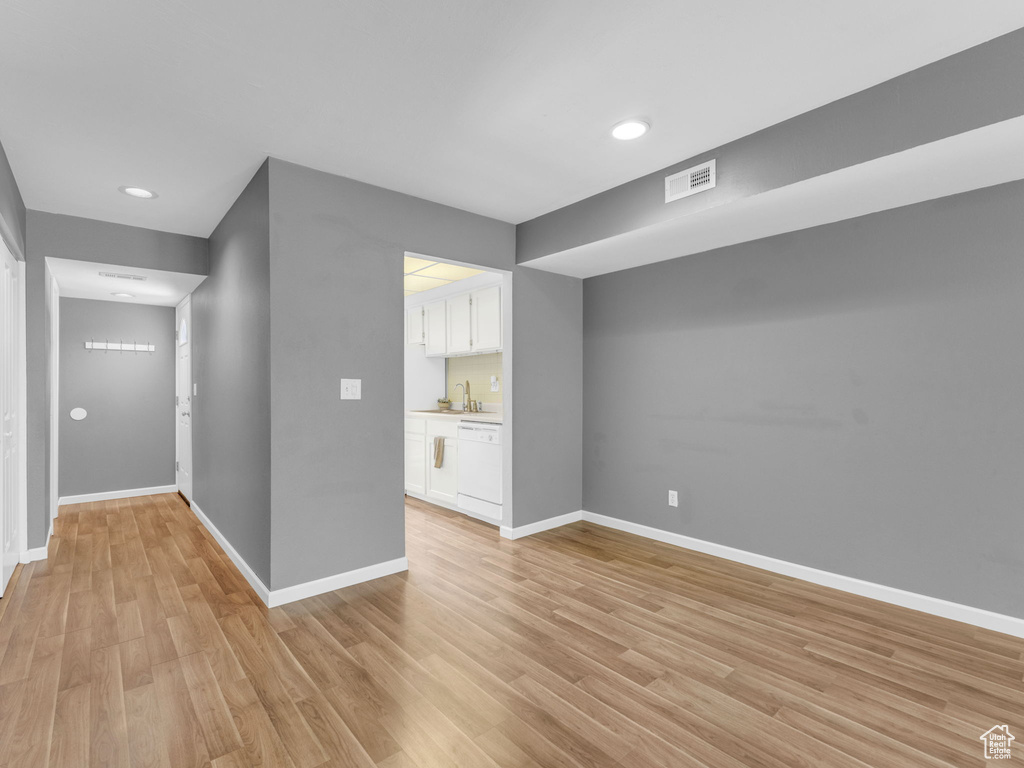 Spare room with light wood-style floors, baseboards, a sink, and recessed lighting