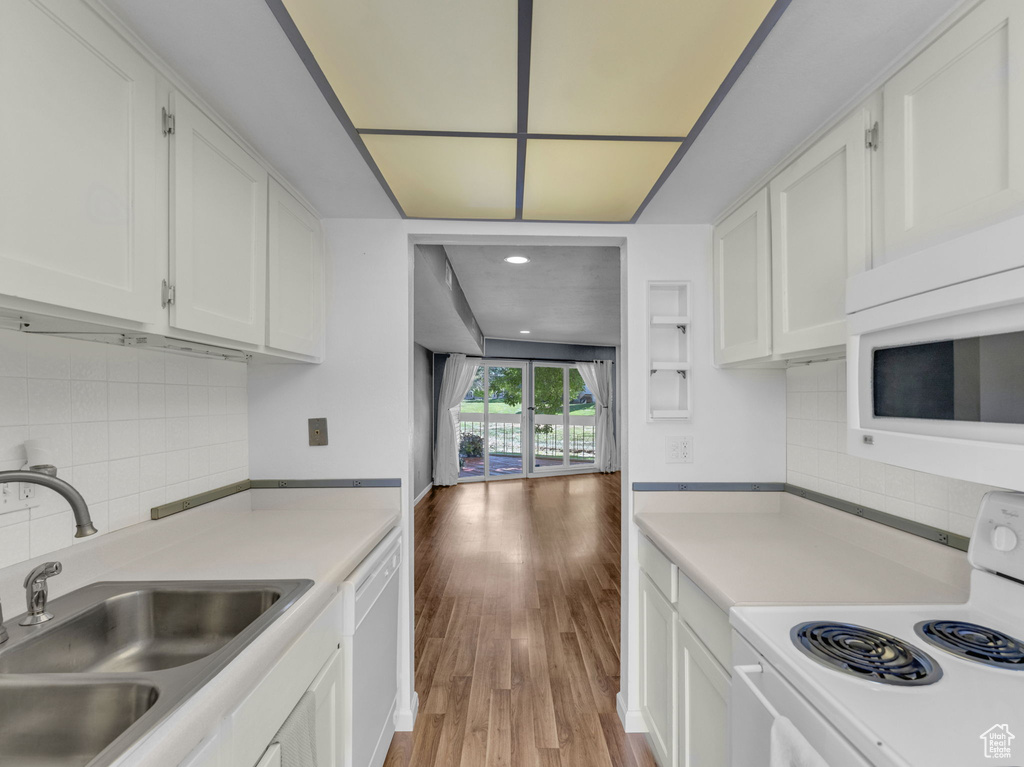 Kitchen featuring white appliances, a sink, white cabinetry, light countertops, and recessed lighting