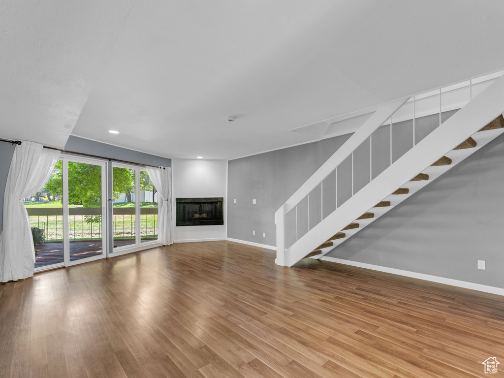 Unfurnished living room featuring baseboards, stairway, wood finished floors, recessed lighting, and a fireplace