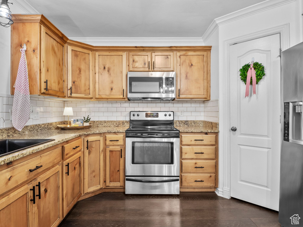 Kitchen with stainless steel appliances, decorative backsplash, light stone countertops, dark wood-type flooring, and crown molding