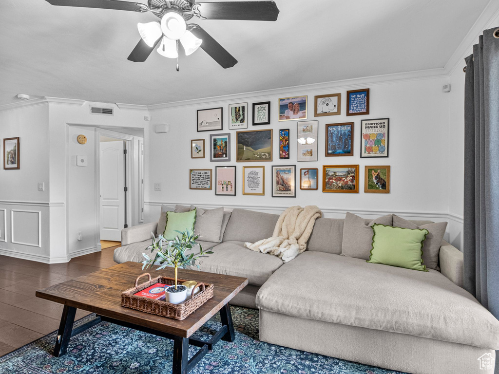 Living area featuring ornamental molding, a ceiling fan, wood finished floors, and wainscoting