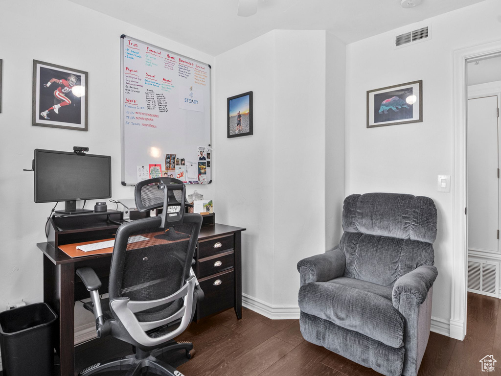 Home office with dark wood-type flooring and baseboards