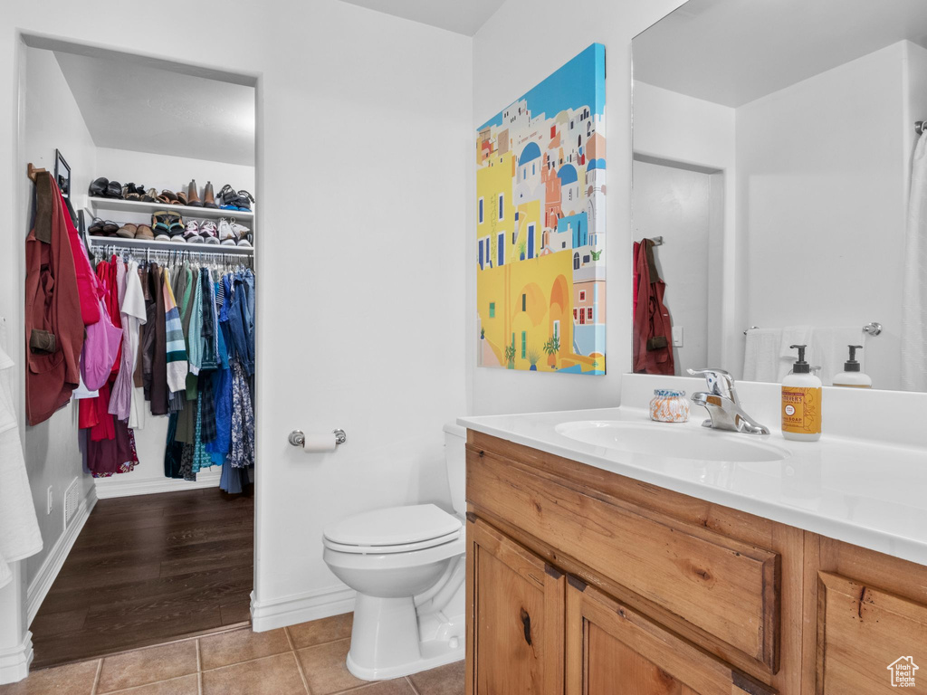 Bathroom with vanity, tile patterned floors, toilet, and a spacious closet