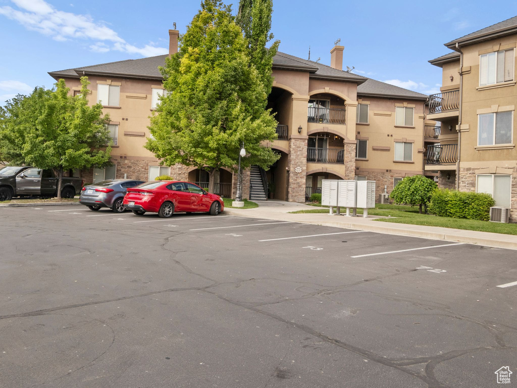 View of property with uncovered parking and cooling unit