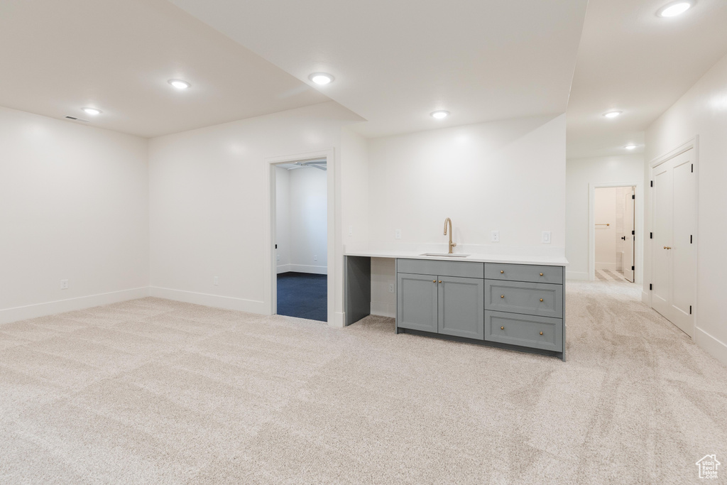 Basement featuring light colored carpet, wet bar, baseboards, and recessed lighting