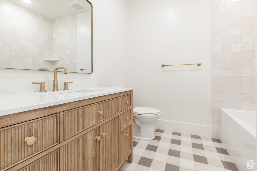 Bathroom with vanity, toilet, tile patterned floors, baseboards, and bathing tub / shower combination