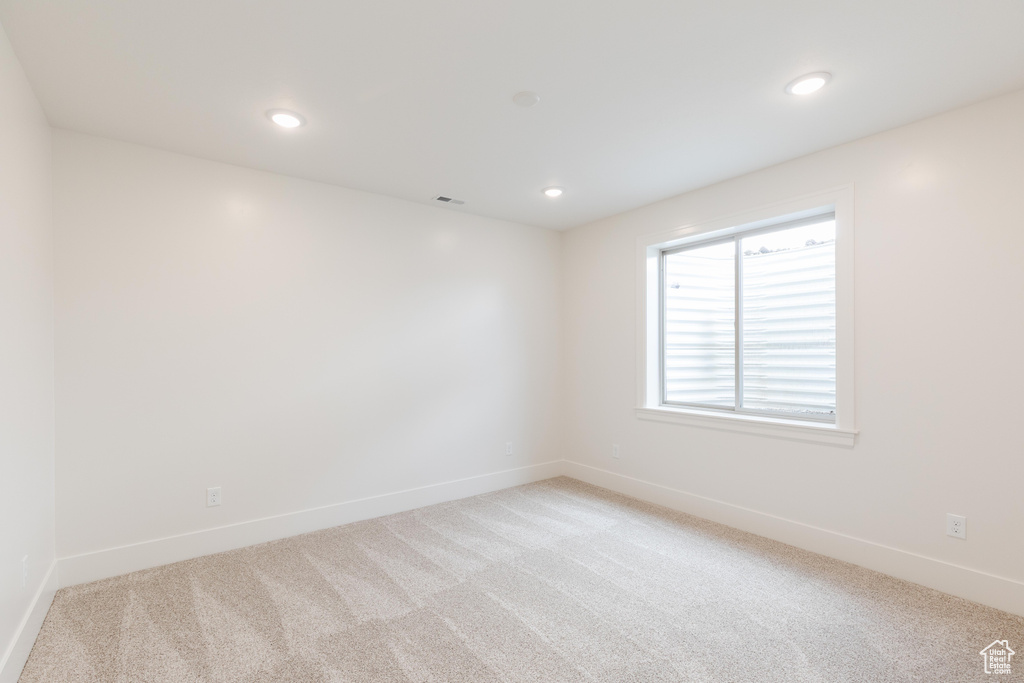 Spare room featuring light carpet, baseboards, and recessed lighting