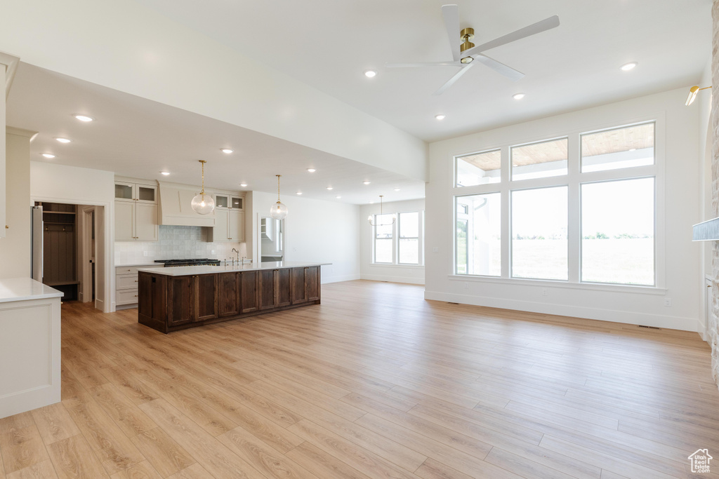 Unfurnished living room with light wood-style floors, a sink, baseboards, a ceiling fan, and recessed lighting