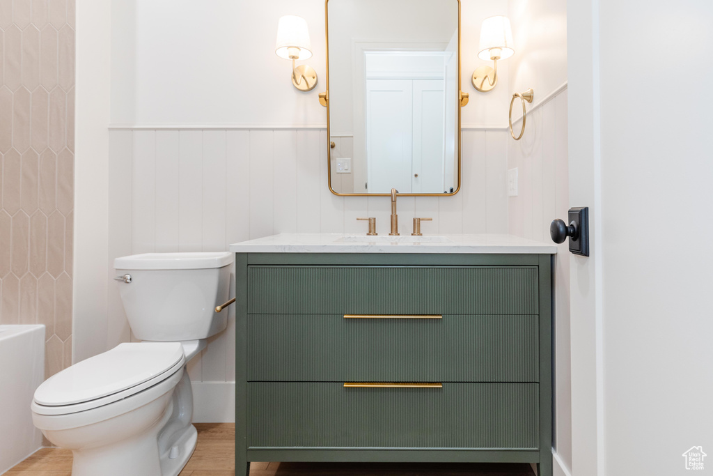 Bathroom with vanity, toilet, a wainscoted wall, and a shower