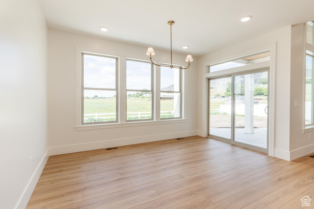Spare room with baseboards, a chandelier, light wood-style floors, and recessed lighting