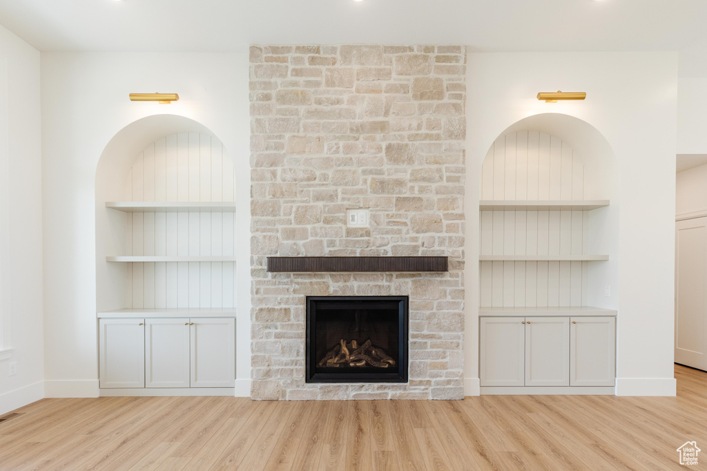 Unfurnished living room with wood finished floors, a fireplace, built in features, and baseboards