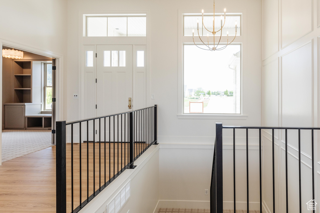 Entrance foyer with a chandelier, a towering ceiling, baseboards, and light wood finished floors