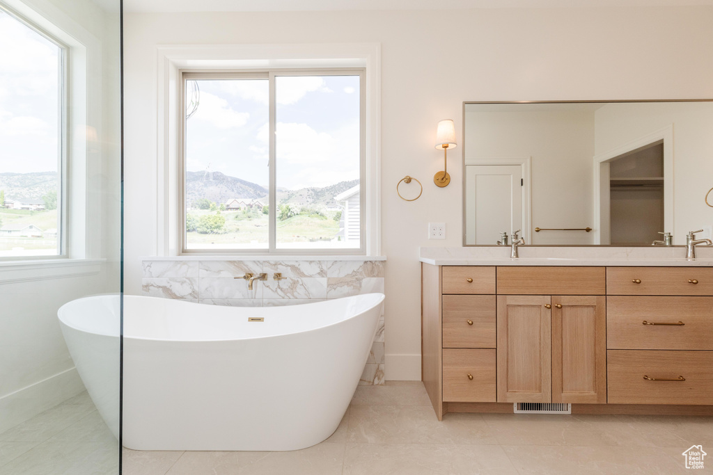 Bathroom with double vanity, a freestanding tub, tile patterned flooring, and a mountain view