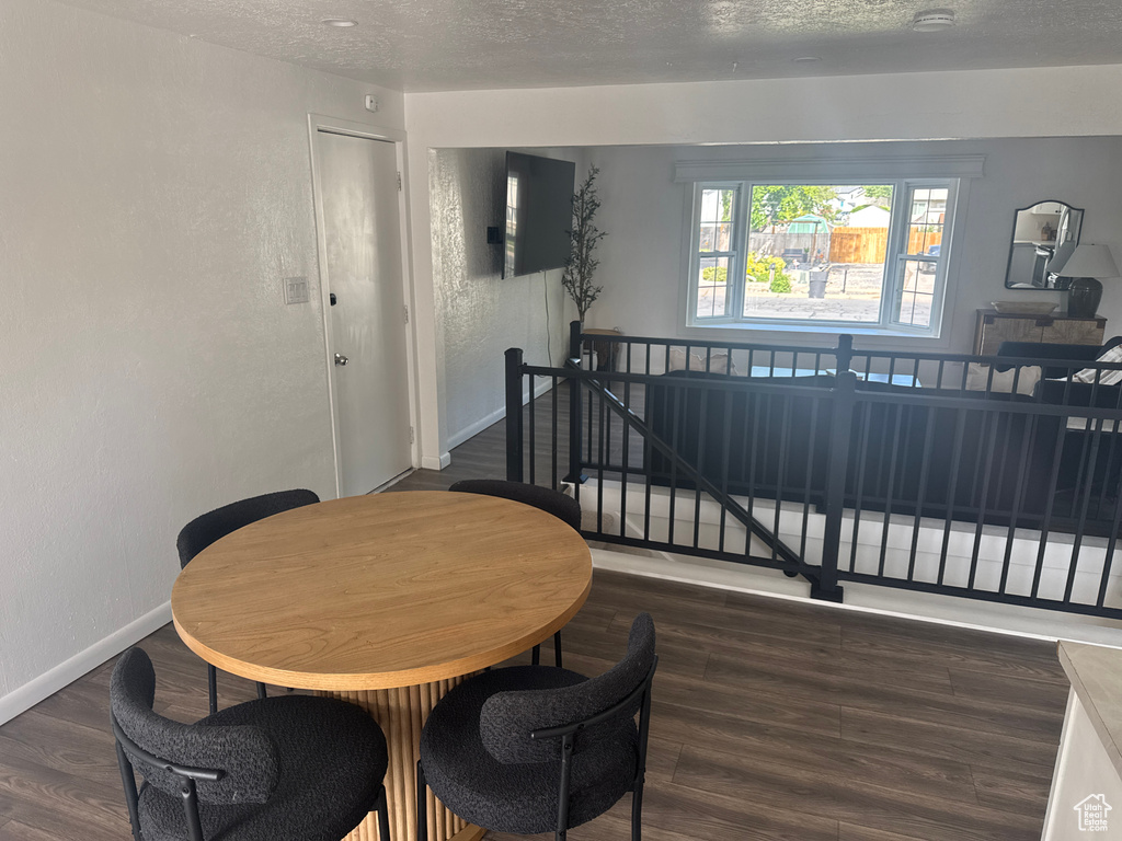 Dining area featuring a textured ceiling, wood finished floors, baseboards, and a textured wall