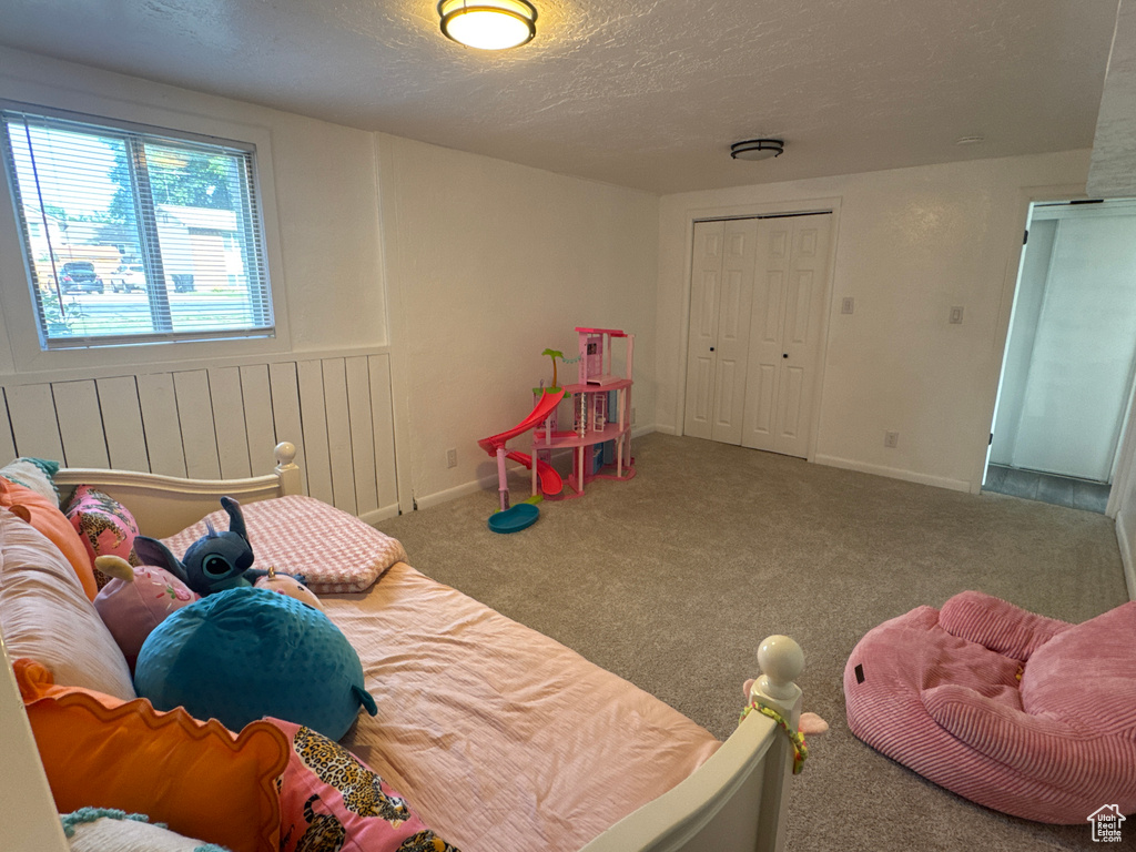 Rec room featuring a textured ceiling, carpet floors, and baseboards