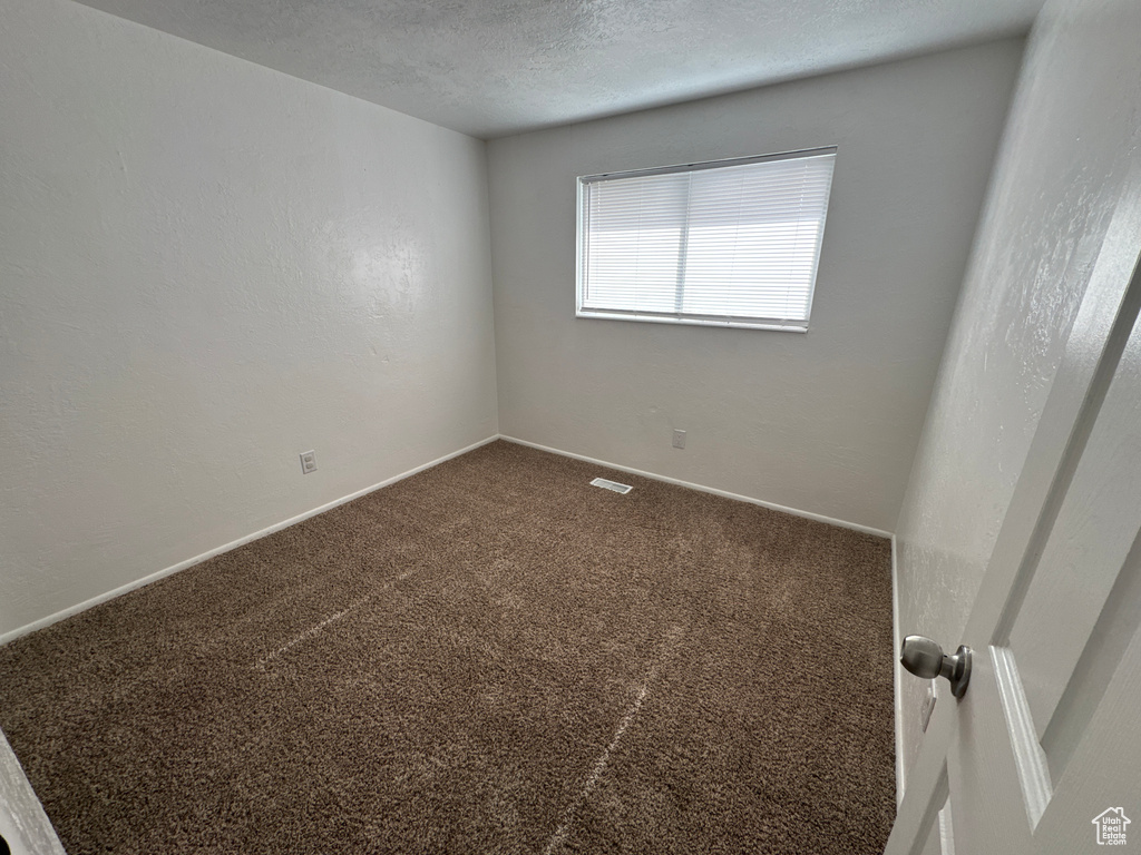 Carpeted spare room featuring baseboards and a textured ceiling