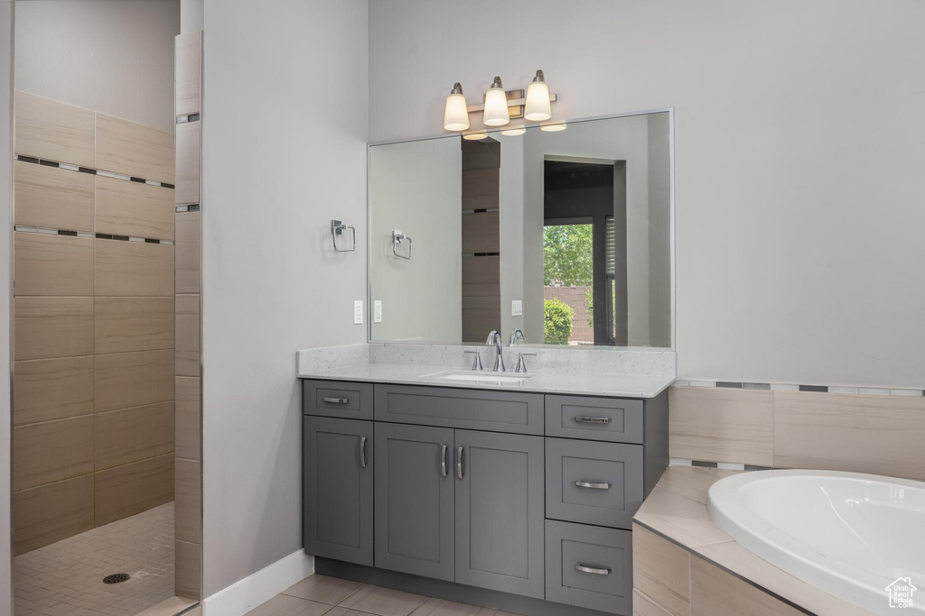 Full bathroom featuring a bath, vanity, tiled shower, and tile patterned floors