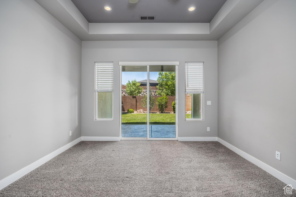 Spare room with a raised ceiling, carpet, recessed lighting, and baseboards