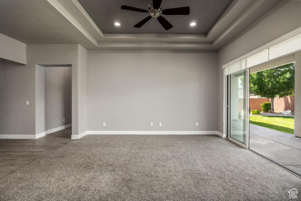 Carpeted spare room with a tray ceiling, a ceiling fan, baseboards, and recessed lighting
