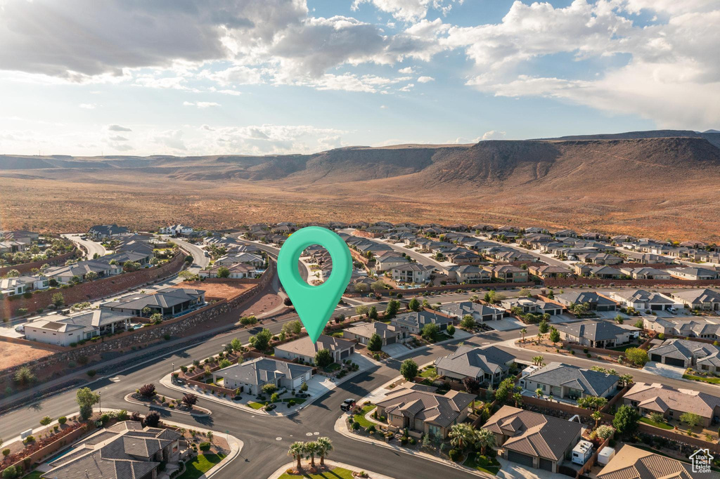 Aerial view of property and surrounding area featuring nearby suburban area and a mountain backdrop