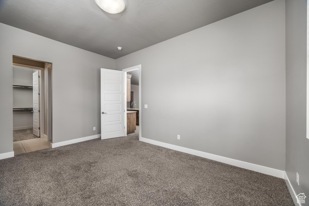 Unfurnished bedroom with carpet flooring, baseboards, and a spacious closet