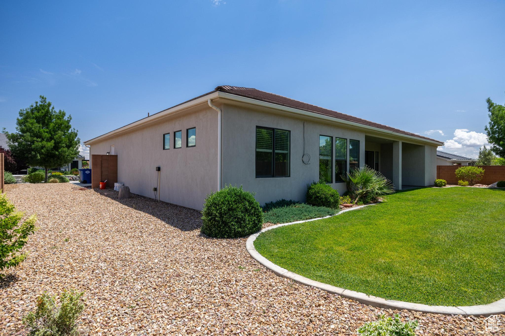 Rear view of house featuring stucco siding and a lawn