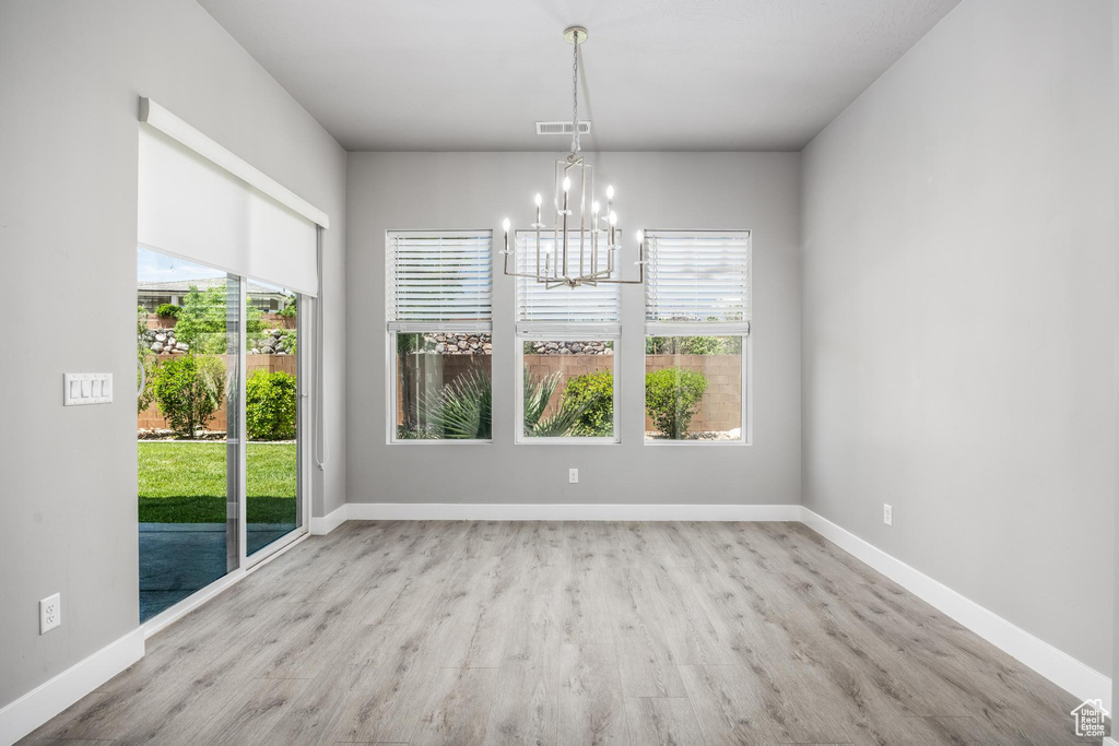 Unfurnished dining area featuring a chandelier, wood finished floors, and baseboards